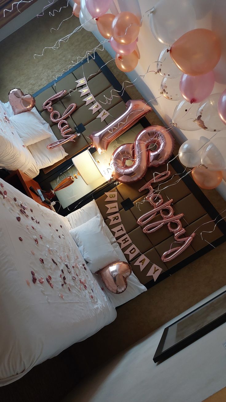 a room with balloons and pink letters on the floor