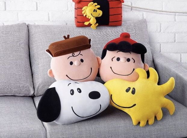 three stuffed animals sitting on top of a gray couch next to a brick wall and potted plant