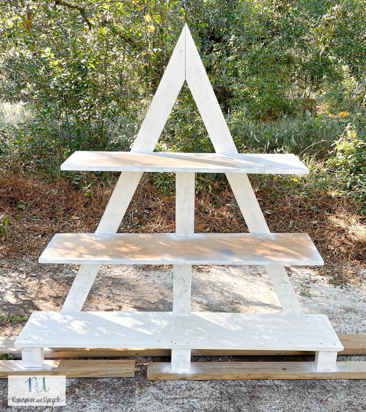 a white wooden christmas tree sitting on top of a pile of wood