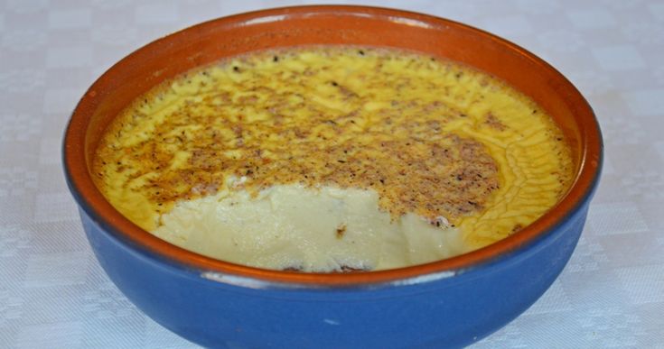 a blue bowl filled with food sitting on top of a white table covered in cloth