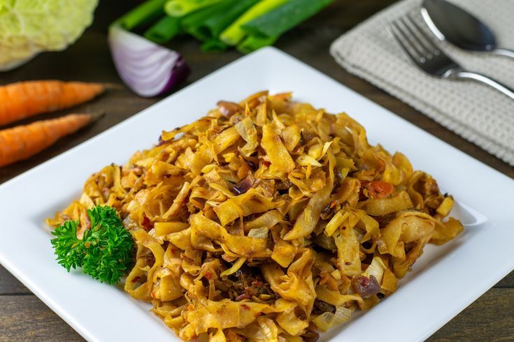 a white plate topped with pasta next to carrots and celery