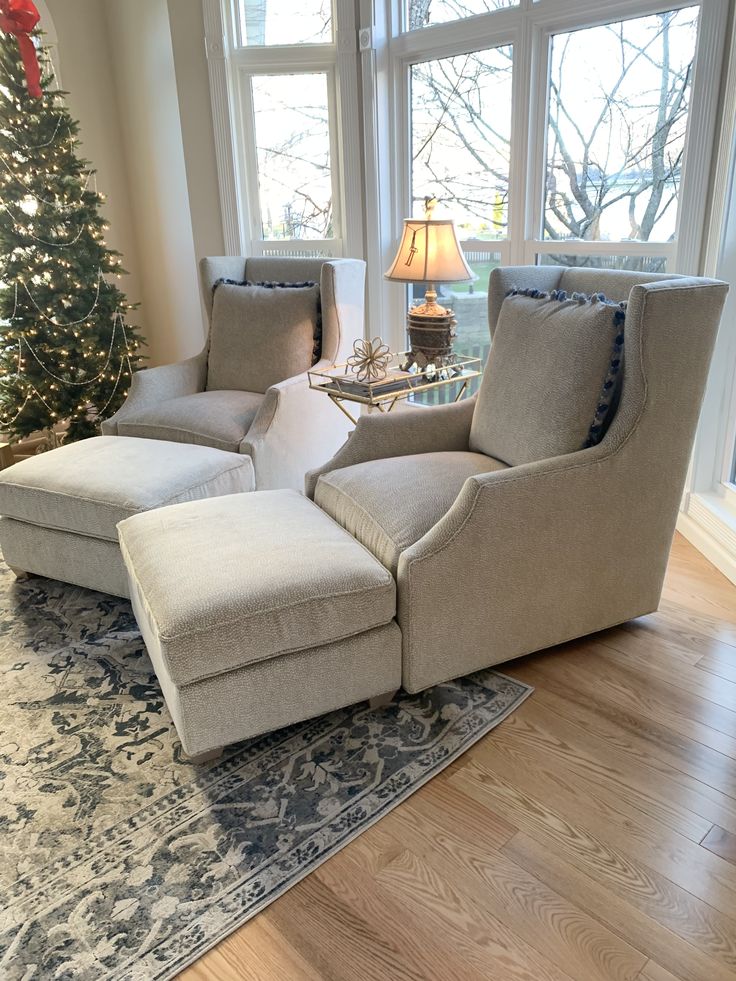 a living room filled with furniture and a christmas tree in front of a window on top of a hard wood floor