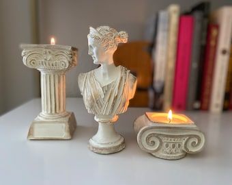 there are two candles that have been placed next to each other on a table with books in the background