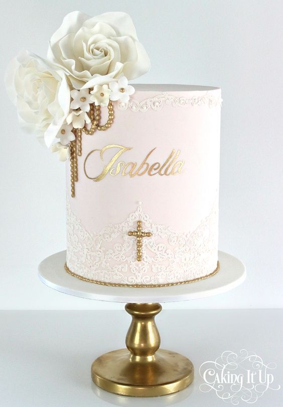 a white cake with gold lettering and flowers on the top is sitting on a stand