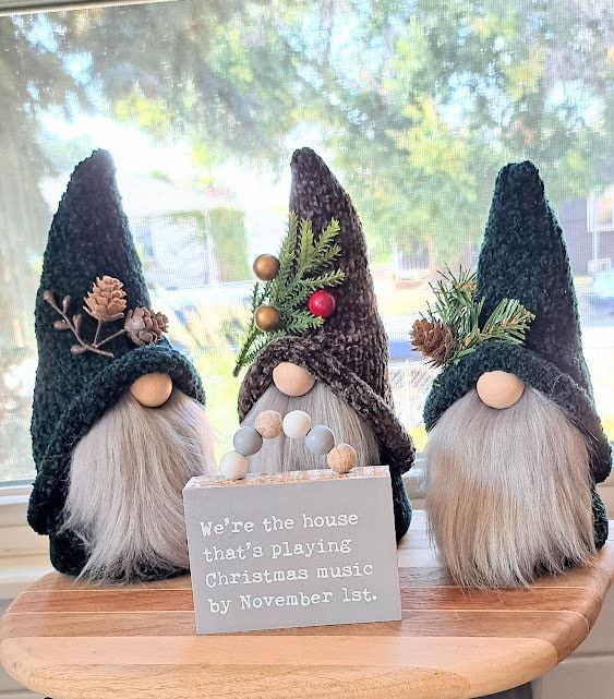 three gnomes are sitting on a table with a sign that says, and one is the house what's playing christmas music by november 1st