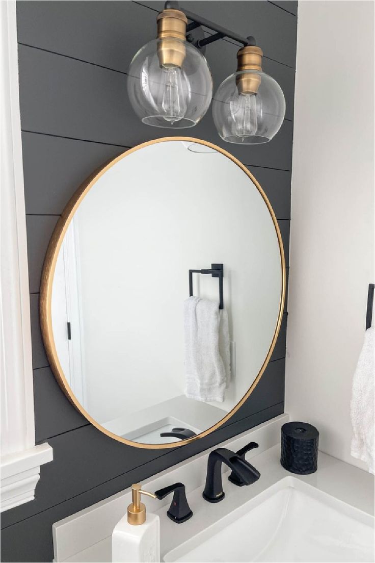 a bathroom with a round mirror and two lights on the wall next to a sink