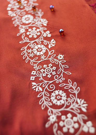 an embroidered red cloth with white flowers and beads on the edge is laying on a table