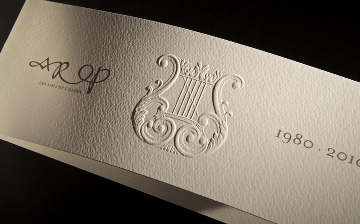 a close up of a business card on a black surface with white paper and silver foil