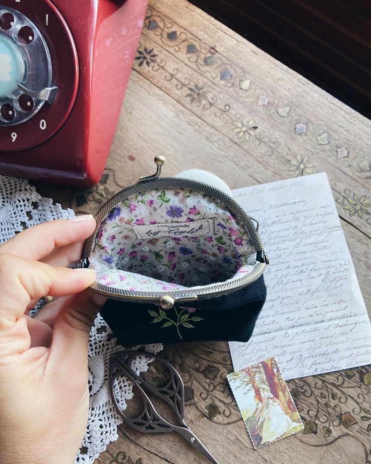 a hand holding a coin purse next to an old phone