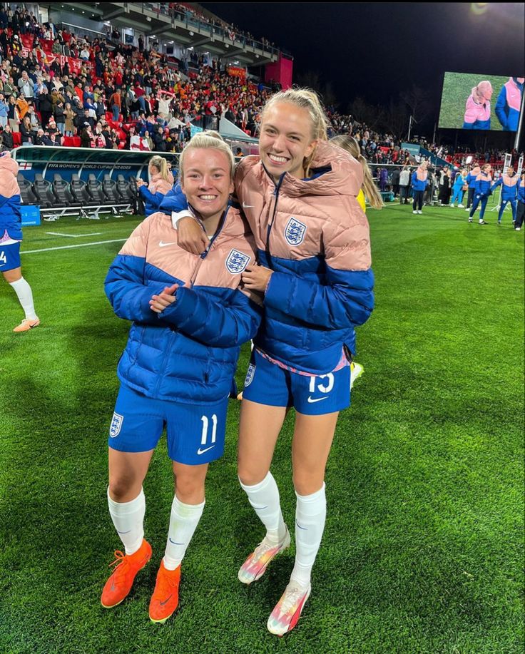 two female soccer players hugging each other on the field