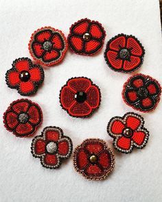 nine red and black beaded buttons arranged in a circle on top of a piece of white paper