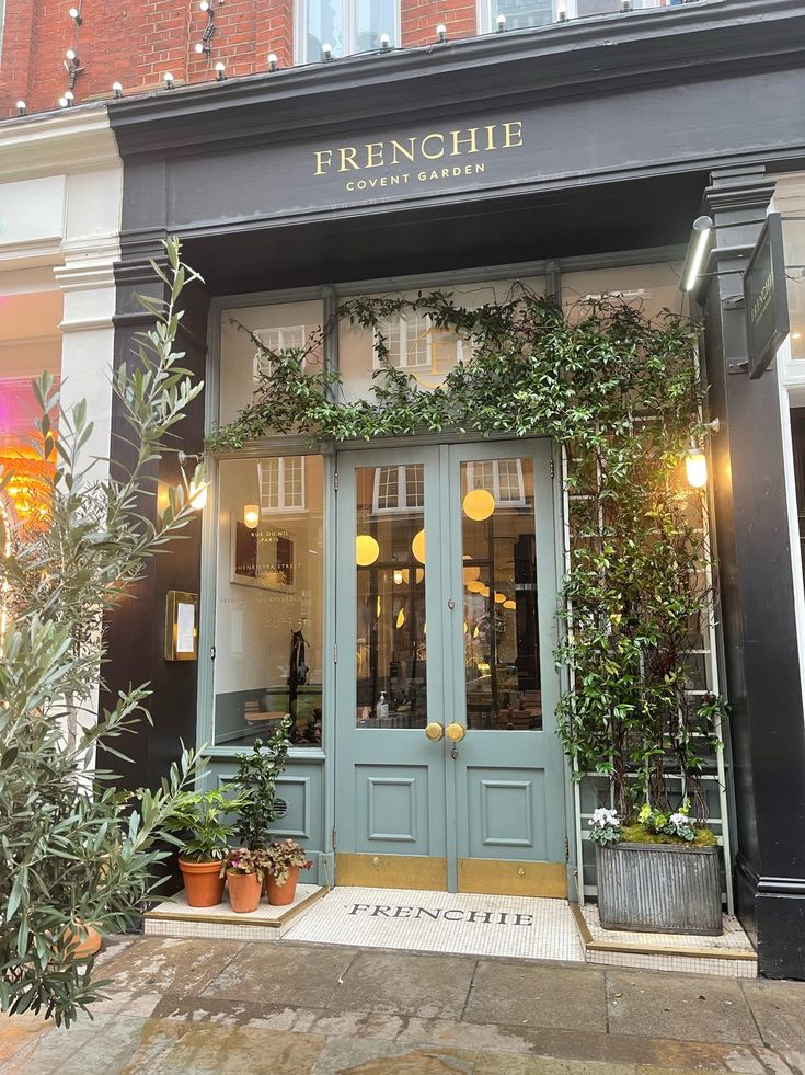 the entrance to a french restaurant with potted plants