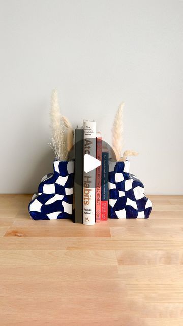 two books are stacked on top of each other in front of a bookend with feathers sticking out of it