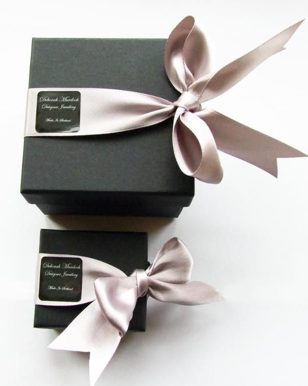 two black boxes with silver ribbons tied around the edges and one has a bow on it