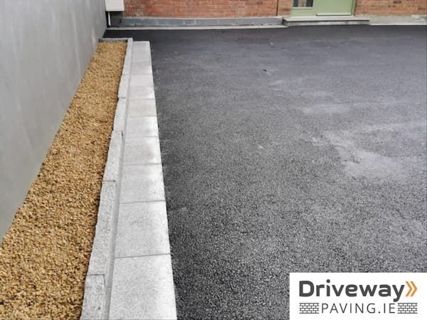 an empty parking lot in front of a brick building with gravel on the ground and door