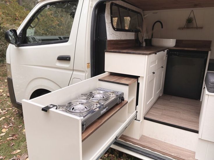 the interior of a camper van with its door open and stove in the back