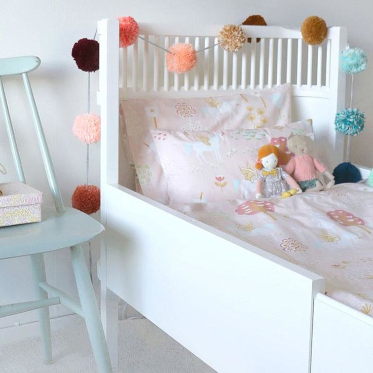 a child's bed with pink and blue decorations on the headboard, next to a rocking chair