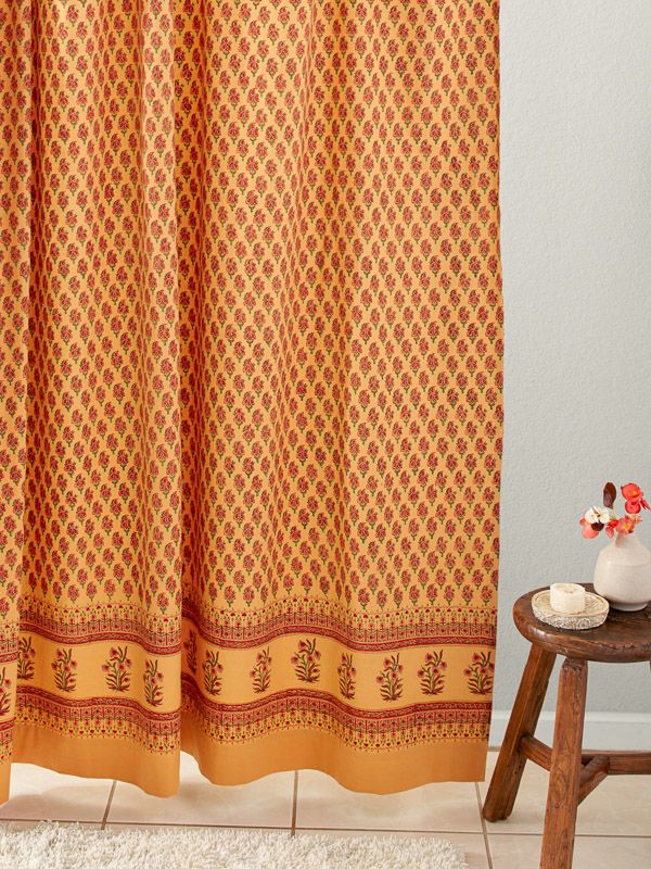 an orange shower curtain in a bathroom next to a stool and vase with flowers on it