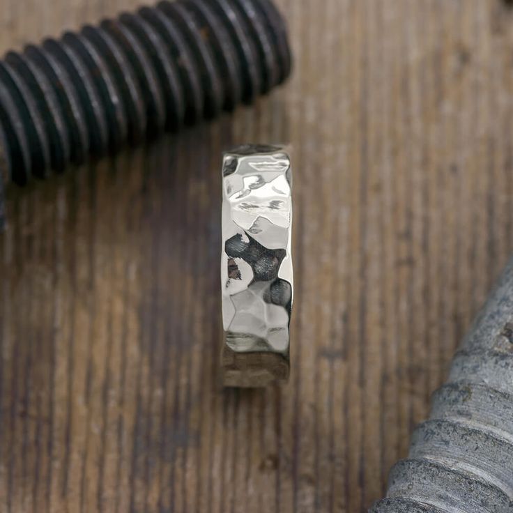 a gold ring sitting on top of a wooden table next to a metal object and pipe