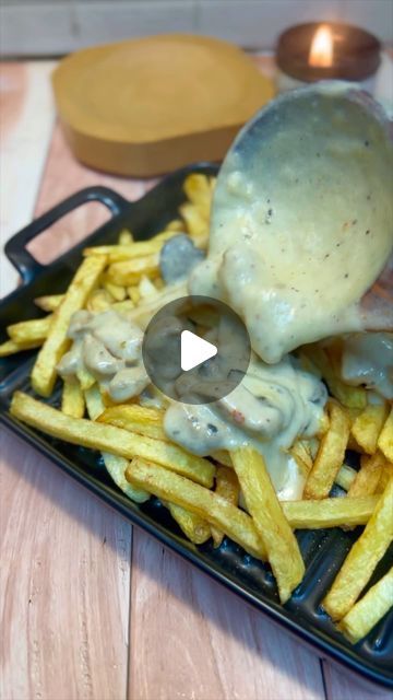 a black plate topped with french fries covered in gravy and melted cheese on top