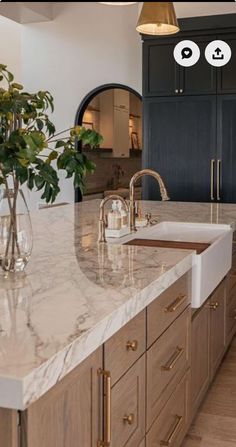 a large kitchen with marble counter tops and wooden cabinets, along with two vases on the island