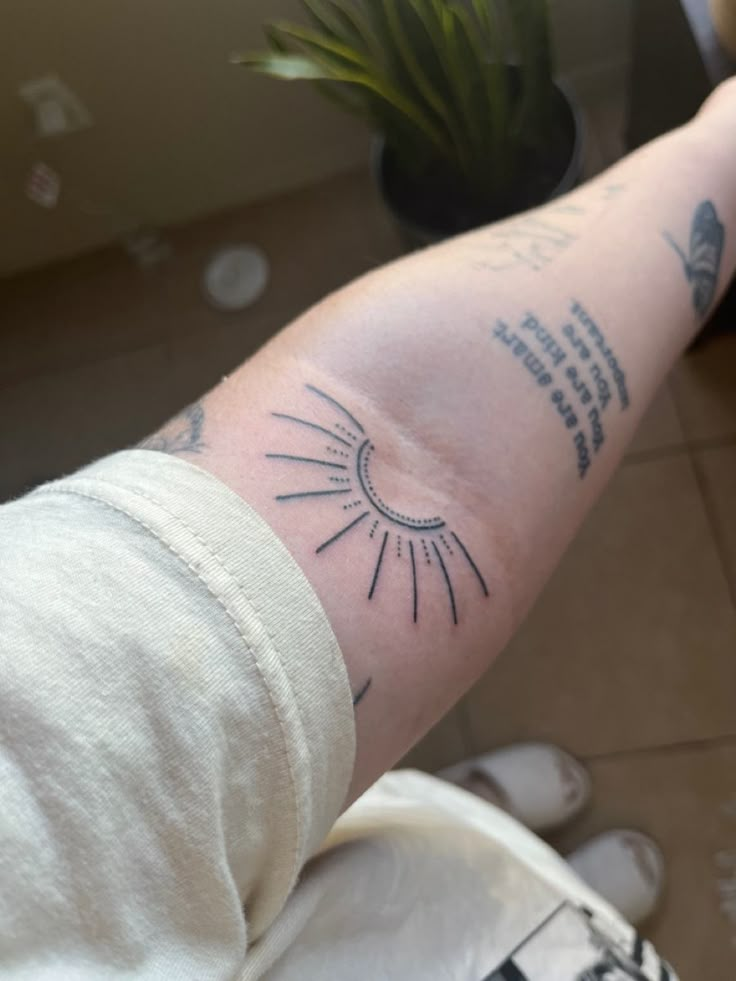 a person with a tattoo on their arm that has an image of the sun in it