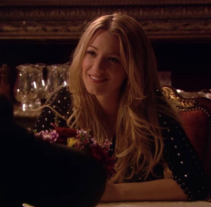 a woman sitting at a table with flowers in her hand