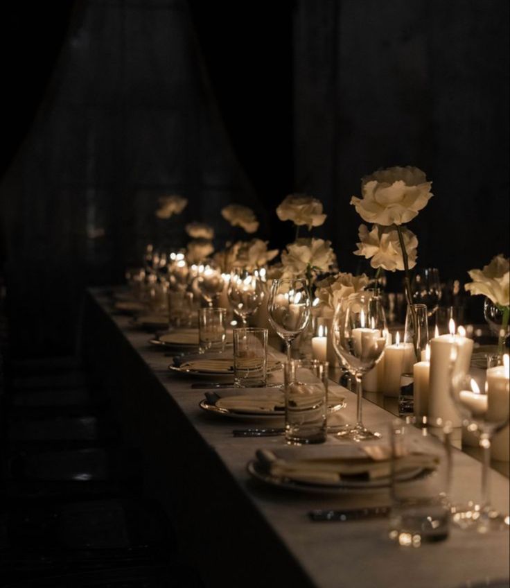 a long table is set with candles and flowers in vases, plates and glasses