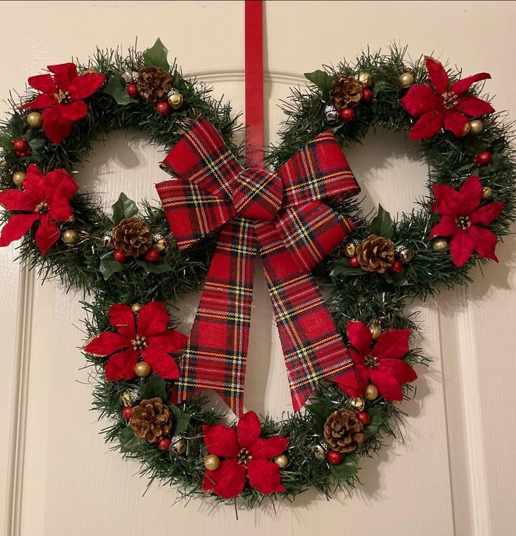 a christmas wreath with poinsettis and pine cones hanging on the front door