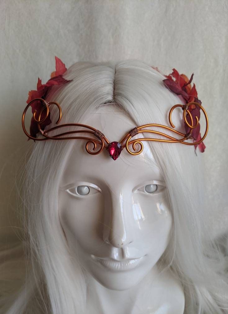 A beautiful, intricate crown with a burgundy crystal decorating the center of the copper wire and autumn leaves surrounding the piece. Eyes will follow the delicate swirls and breezy leaves as the garland decorates your head, perfect for renaissance fairs, weddings, cosplay, or any event of your choosing! Choose between a Burgundy or Red Crystal! Fae Characters, Red Crowns, Autumn Crown, Fantasy Crowns, Copper Autumn, Copper Crown, Elven Tiara, Woodland Crown, Wire Crown