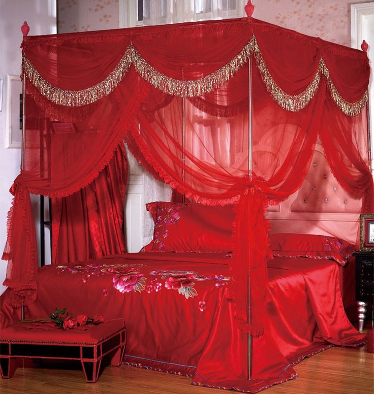 a red canopy bed sitting on top of a wooden floor