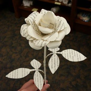 a person is holding a paper rose in their hand with the words written on it