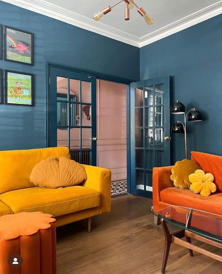 a living room with blue walls and orange couches