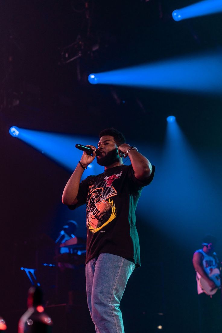 a man standing on top of a stage holding a microphone in front of his face