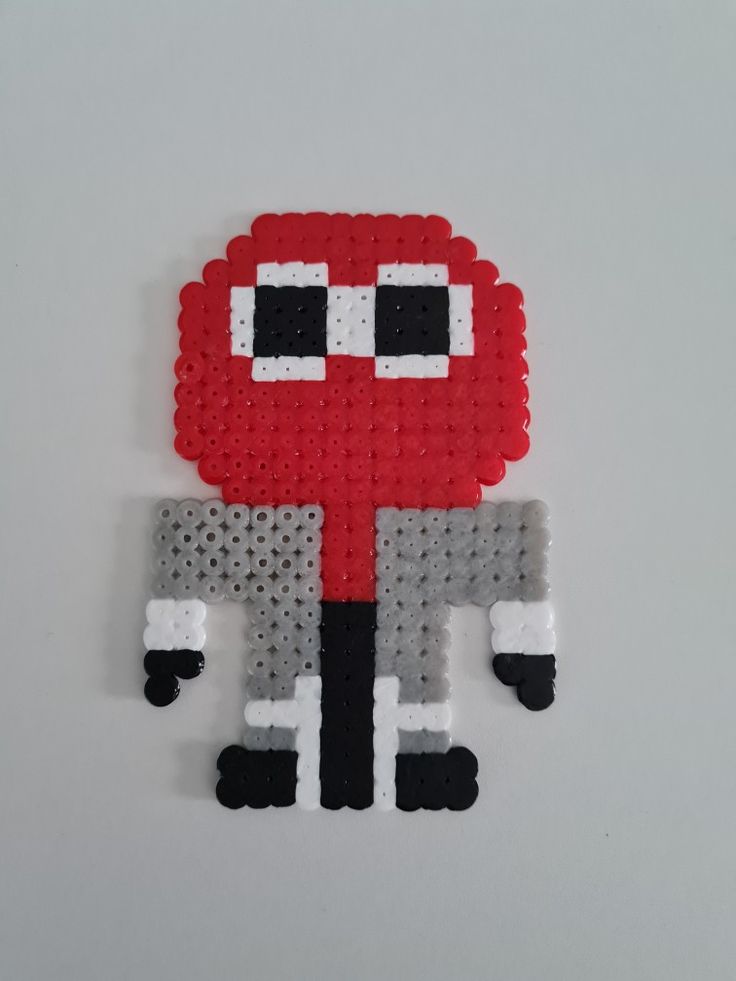 a red and black pixel art piece on a white surface with one eye open, the other half closed