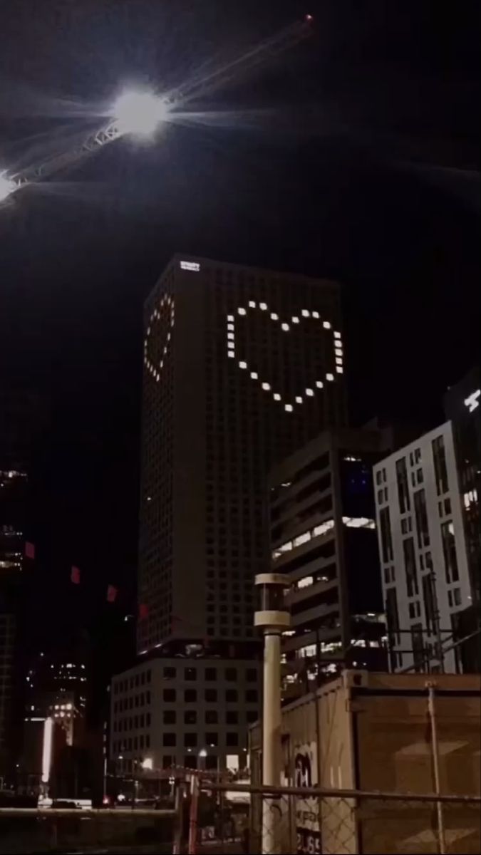 the city skyline is lit up at night with bright lights and buildings in the background