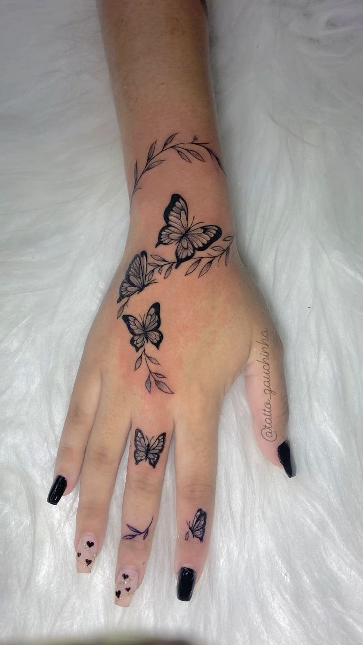 a woman's hand with butterfly tattoos on it