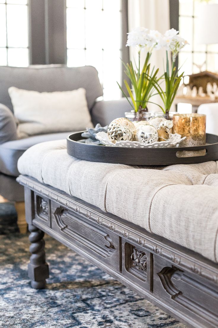 a tray with some flowers on it sitting on a bench in front of a couch