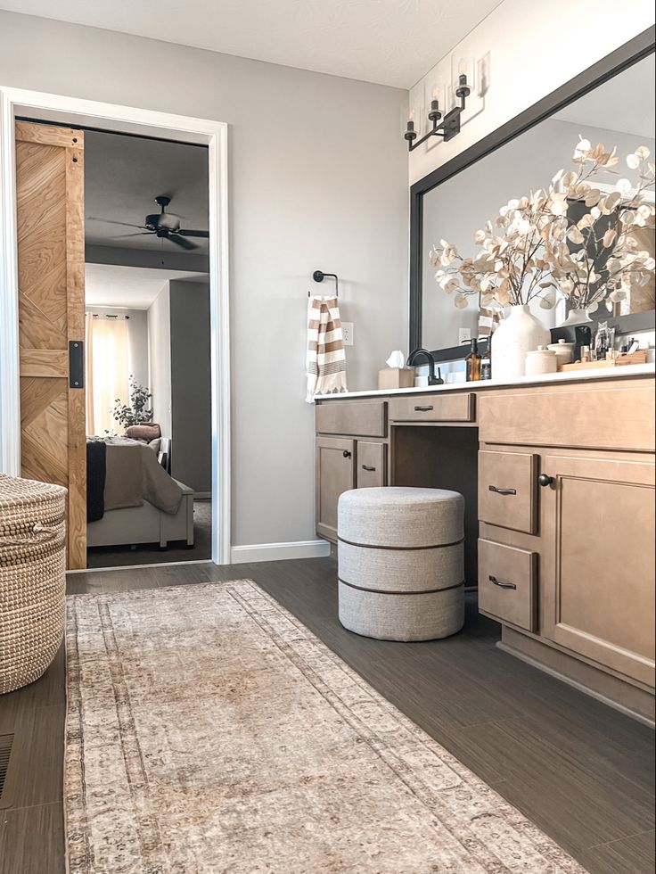 a bathroom with a large rug and wooden cabinetry in the corner, along with a mirror on the wall