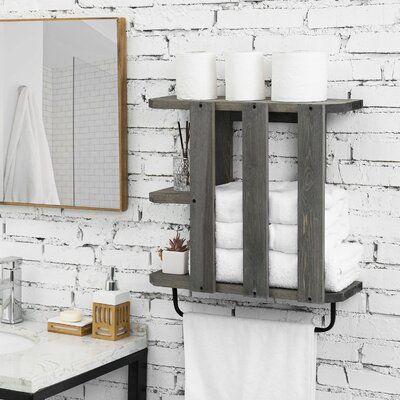 a bathroom with white brick walls and wooden shelves holding towels, toiletries and candles