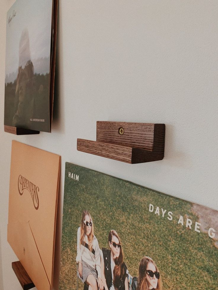 three photos hang on the wall above a shelf with two pictures and a wooden object