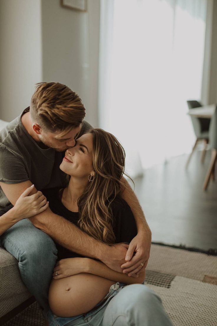 a man and woman sitting on a couch cuddling