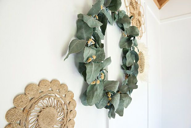 a wreath is hanging on the wall next to a white door with a doily