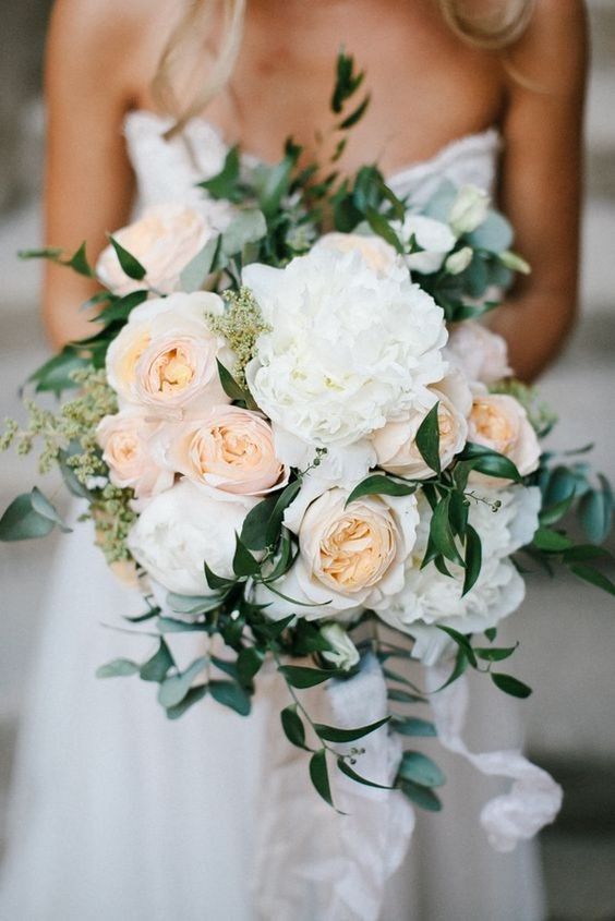 a bridal holding a bouquet of white and peach flowers