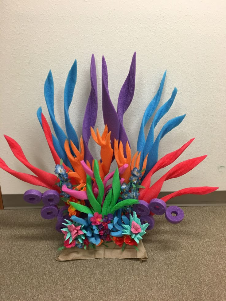 an arrangement of multicolored feathers on display in a room next to a wall