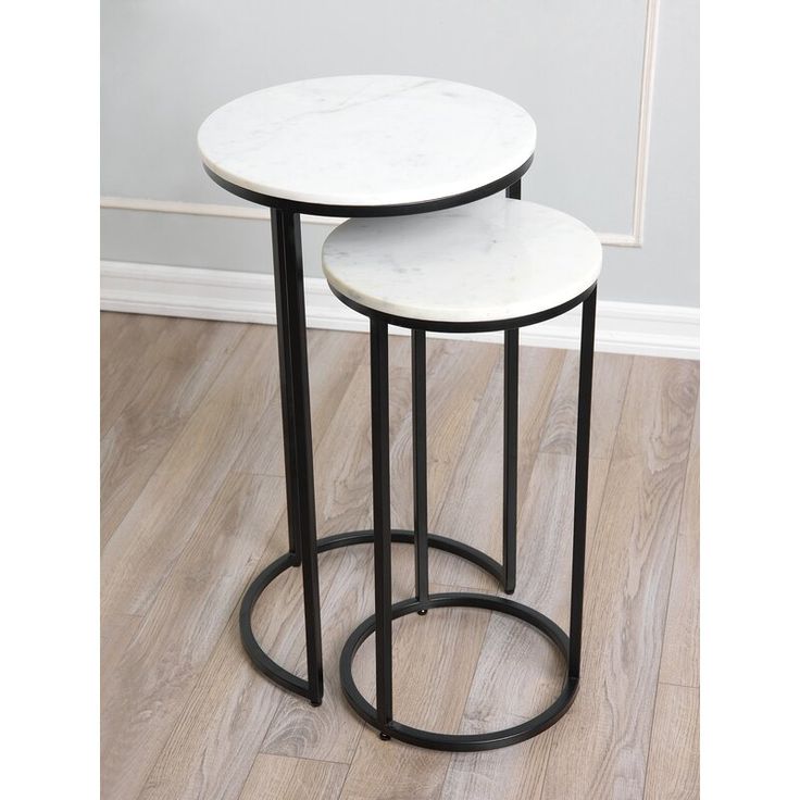 two white marble side tables sitting on top of a hard wood floor