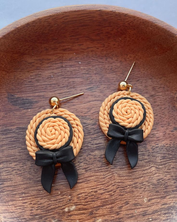 pair of earrings with black ribbon and bow on wooden surface, close - up view