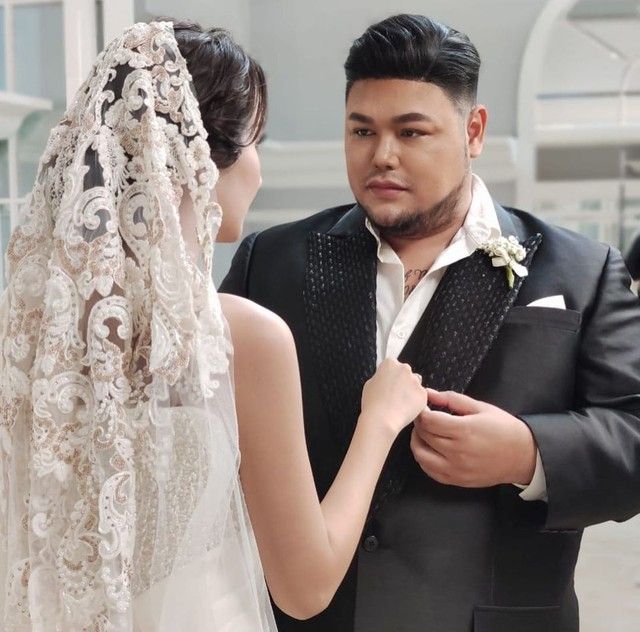 a man and woman standing next to each other in front of a mirror wearing veils