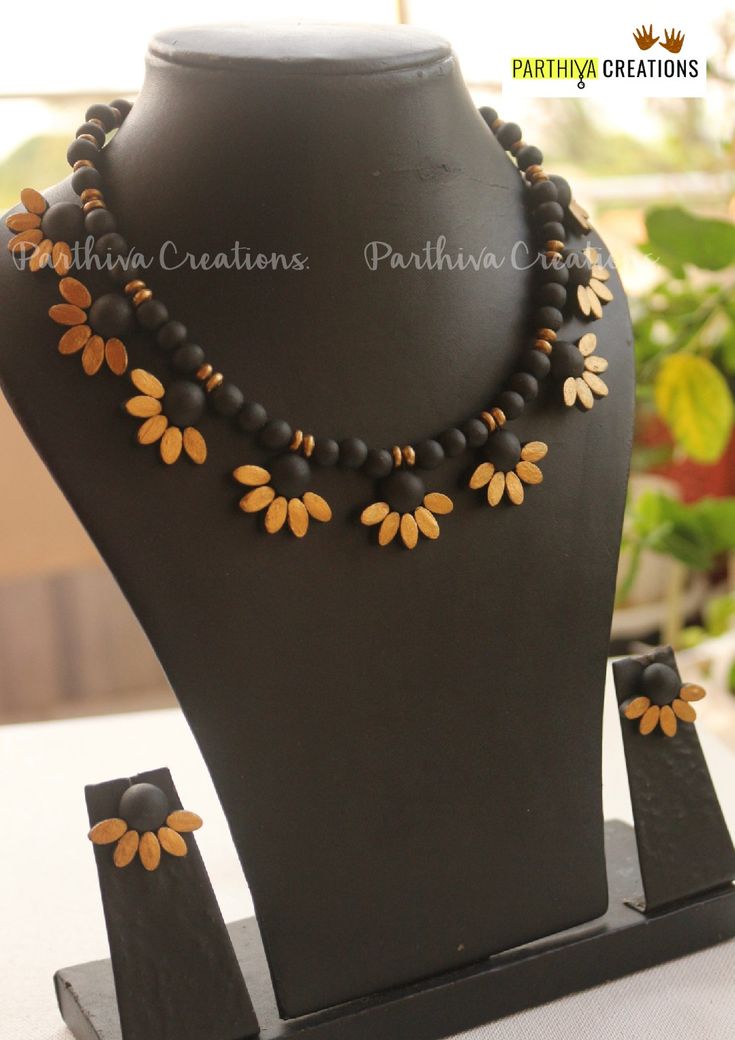 a necklace and earring set is displayed on a mannequin with black beads