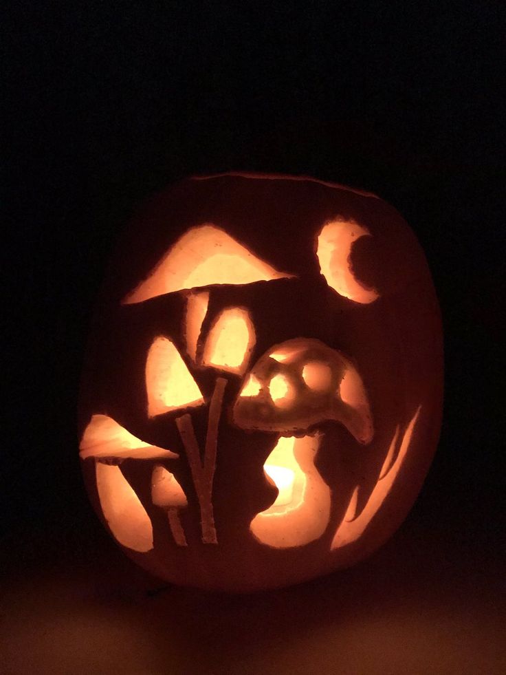 a pumpkin carved to look like it has mushrooms on it and is lit up in the dark